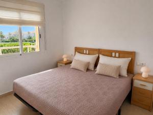 a bedroom with a bed with two lamps and a window at Dénia Palm Garden Apartment Pool & Parking in Denia