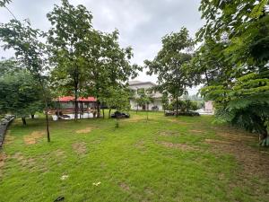 a yard with trees and a building in the background at Moksha farms -3bhk private villa with pool and nature in Pālghar