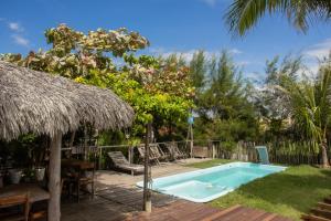 a swimming pool in a yard with chairs and a umbrella at Pousada Delta Chalés in Tutóia