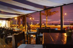 a restaurant with tables and chairs and a view of the beach at Club Colonial Hotel in Huanchaco