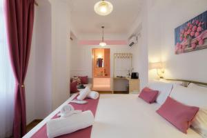 a bedroom with a large white bed with pink pillows at Aphrodite luxury rooms in Mytilene