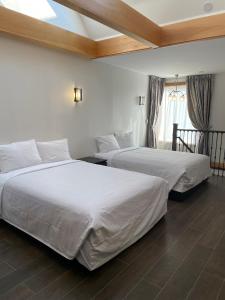 two beds in a hotel room with white sheets at Cabbagetown Inn in Toronto