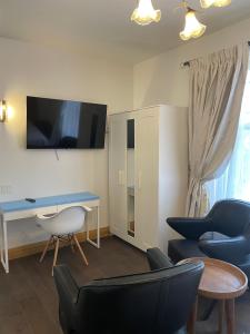 a living room with a desk and chairs and a tv at Cabbagetown Inn in Toronto