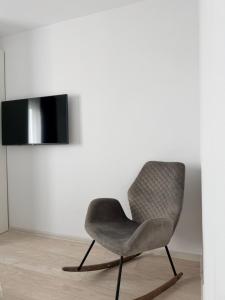 a gray chair sitting in a room with a tv at Apartamentul Castanilor in Ploieşti