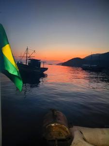 a boat sitting in the water at sunset at Mata Virgem Hostel e Pousada in Abraão