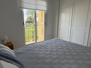 a bedroom with a bed and a large window at Dénia Palm Garden Apartment Pool & Parking in Denia