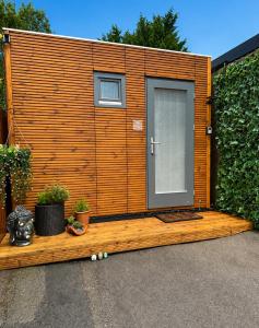 a wooden cabin with a door and some plants at The Snug in Yeovil