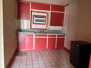 a red kitchen with a sink and a microwave at Holiday Motel Tulsa OK in Tulsa