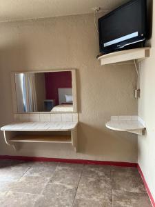 a room with a mirror and a tv on a wall at Holiday Motel Tulsa OK in Tulsa