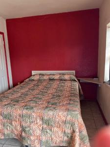 a bedroom with a bed with a red wall at Holiday Motel Tulsa OK in Tulsa