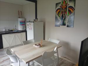 a kitchen with a wooden table with white chairs at El Refugio Tapalque in Tapalqué