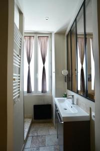 a bathroom with a sink and two windows with curtains at T2 intra muros clim et cour ombragée in Avignon +9 photos