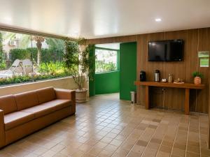 a lobby with a couch and a flat screen tv at Caruaru Pallace Hotel in Caruaru