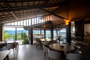 a restaurant with tables and chairs and large windows at Casarão Alpina in Mucugê