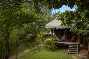 a small hut with a hammock in a garden at Pousada Delta Chalés in Tutóia