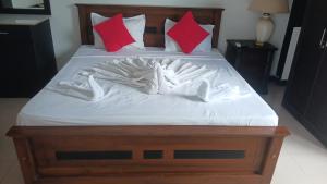 a bed with white sheets and red pillows at Kenrish Hotel in Wadduwa