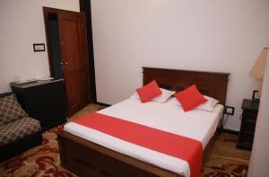 a bedroom with a bed with two red pillows at Kenrish Hotel in Wadduwa