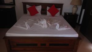 a bed with white sheets and red pillows at Kenrish Hotel in Wadduwa
