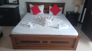 a bed with white sheets and red pillows at Kenrish Hotel in Wadduwa