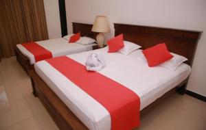 two beds in a room with red and white sheets at Kenrish Hotel in Wadduwa