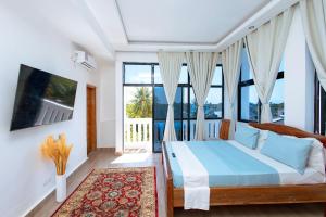 a bedroom with a large bed and large windows at Diani Luxe Villa in Galu