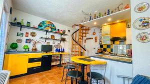 a kitchen with yellow cabinets and a counter with stools at Edelweiss - Maison dOc in Oulx