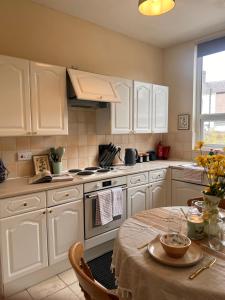 a kitchen with white cabinets and a table and a stove at The Blackburn 2 Bedroom House in Cherry Tree +12 photos