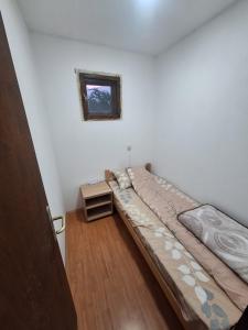 a small bedroom with a bed and a small window at Radnicki smestaj in Prilike