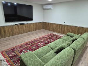 a living room with a green couch and a flat screen tv at Villa by HomeLand in Khujand