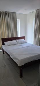 a bed in a bedroom with white sheets and curtains at Lucy Residences in Ernakulam