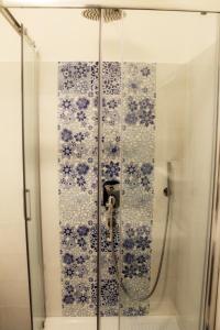 een douche met blauwe en witte tegels op de muur bij Il Vecchio e Il Mare Maratea in Maratea