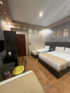 a hotel room with two beds and a table and a desk at Cairò Plàza, Ravexa Hotel in Cairo