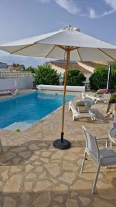 an umbrella and chairs next to a swimming pool at Villa ensoleillée in Ifach +18 photos