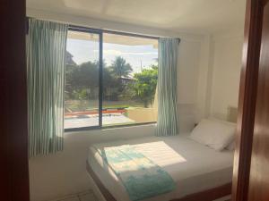a bedroom with a bed and a large window at Hotel La Tolita in Atacames
