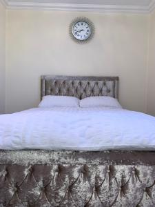a bedroom with a bed with a clock on the wall at Williton Guest House in Luton
