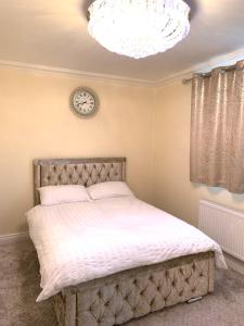 a bedroom with a bed and a clock on the wall at Williton Guest House in Luton