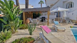 a patio with chairs and a table and a pool at Villa ensoleillée in Ifach
