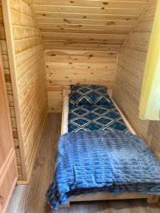 a bed in a room with a wooden wall at Dolina Nataci in Nidzica