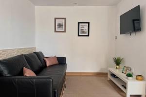 a living room with a black couch and a tv at Casa Pepe in Ourense
