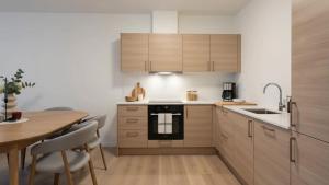 a kitchen with wooden cabinets and a table and a stove at The Haven II - Cozy 2BR Voss - The Voss Collection in Vossevangen +16 photos