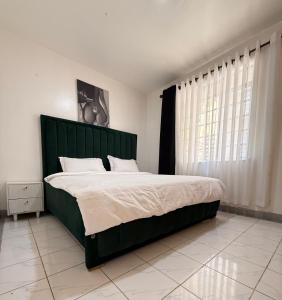 a bedroom with a large bed with a green headboard at Tulia Retreats in Syokimau