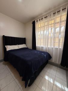 a bedroom with a bed and a window with curtains at Tulia Retreats in Syokimau
