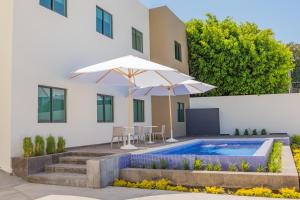 a house with a swimming pool and an umbrella at Hm Express in Colima