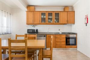 a kitchen with wooden cabinets and a wooden dining table at Cinfães Centro Stay in Cinfães +1 photo