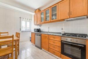 a kitchen with wooden cabinets and a stove top oven at Cinfães Centro Stay in Cinfães