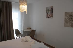a room with two towels on a bed with a chandelier at Lyra Apartments Tilos in Livadia