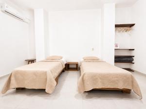 a row of beds in a room with white walls at Galápagos Downtown Suite in Puerto Ayora