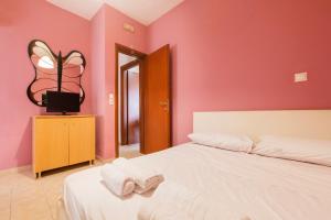 a bedroom with pink walls and a bed with towels on it at Dolphins maisonette Rhodes in Ialysos