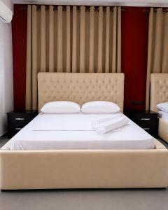 a bedroom with a large bed with white sheets at Hotel Albsin in Vlorë