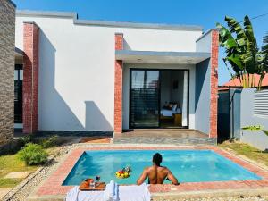 a man sitting in a swimming pool in a house at Shubbys Villa in Dar es Salaam